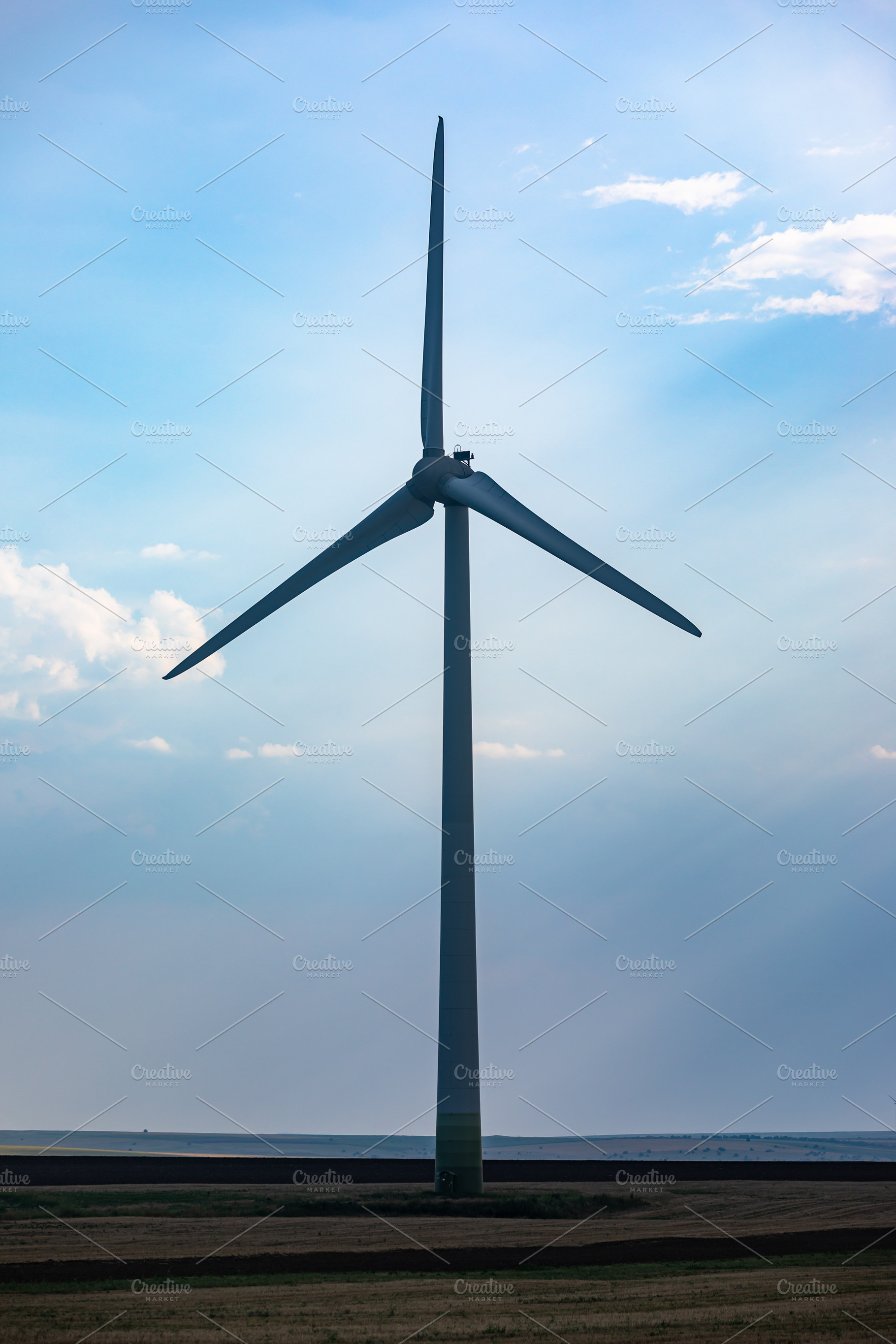 Tall wind turbine stands in a rural field under a partly cloudy sky, symbolizin, a Technology Photo by Ales Munt