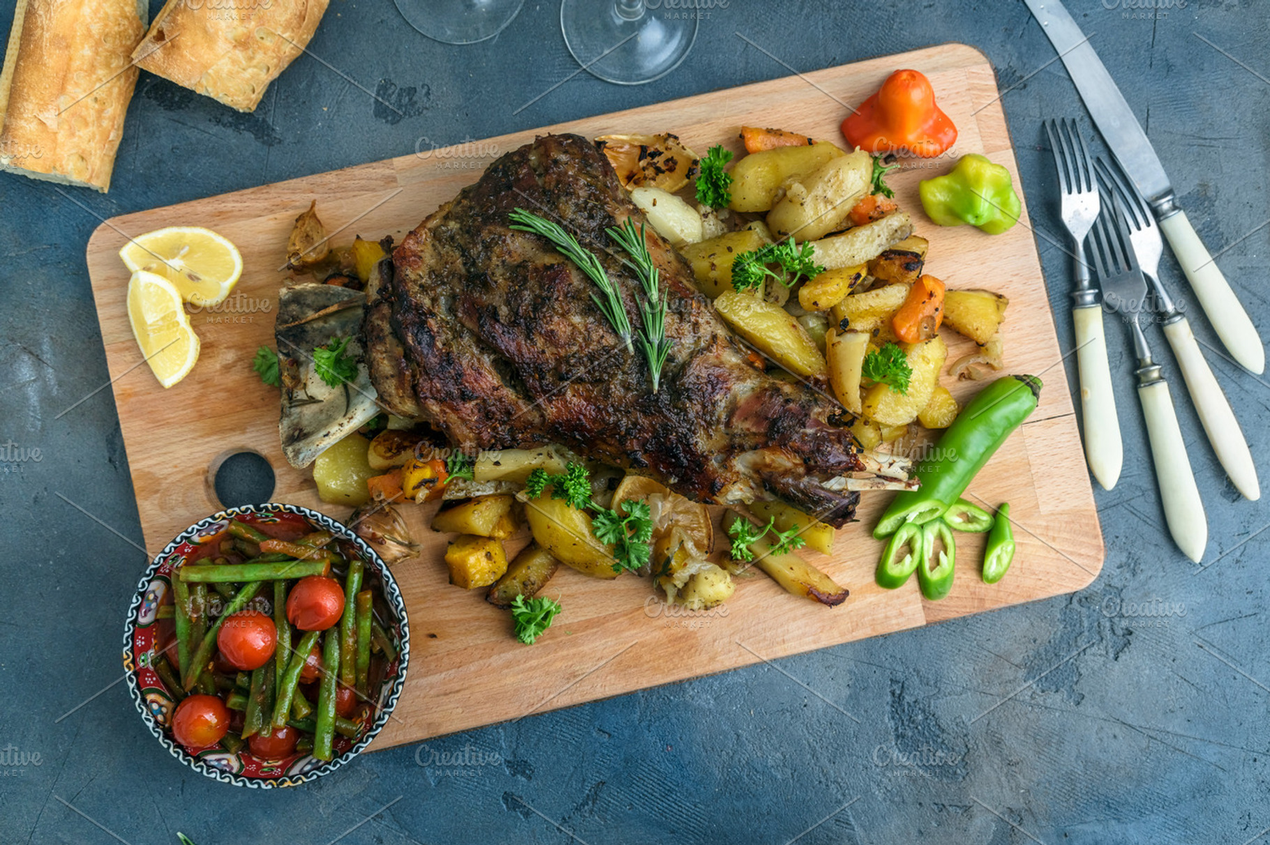 Roast shoulder of lamb on baked potato and carrots wooden board top view, a Food & Drink Photo by Konstantin K.