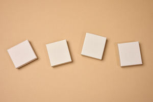 Four beige square cardboard boxes on a beige background., a Background Photo by ndanko