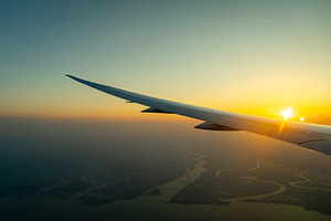 Airplane wing above Osaka coast during sunset descent flight, a Nature Photo by GoodGoods