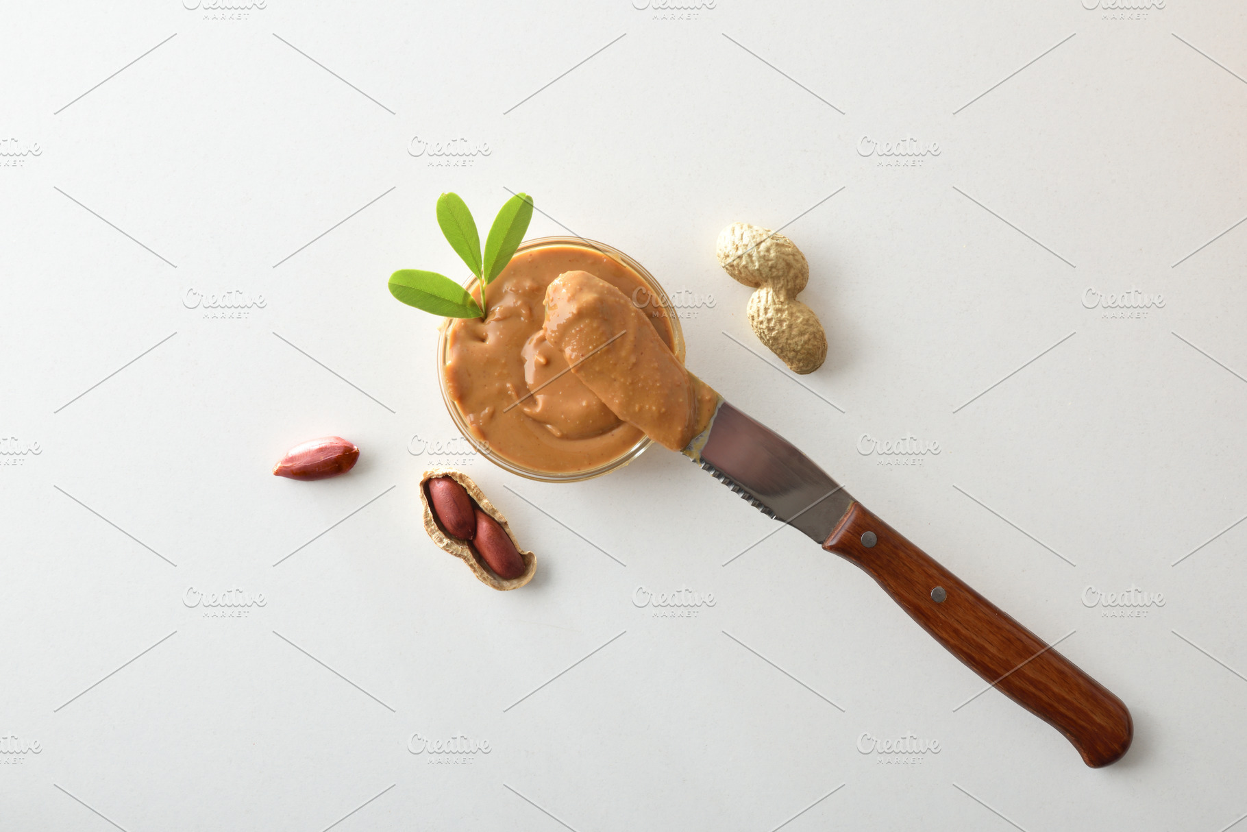 buttered knife resting on a bowl of peanut butter isolated, a Food & Drink Photo by Davizro's Market