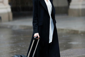 beautiful young woman walks on sideway in city center with suitc, a Photo by WorldOfPhotos