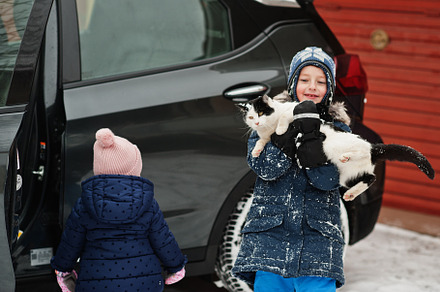 Boy with cat on hands against car in the yard of house at winter, a Person Photo by AS photostudio