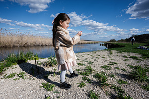 Young girl standing by a river on a sunny day outdoors in nature wearing a coat, a Person Photo by AS photostudio