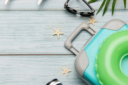 Travel accessories lying on wooden background for summer vacatio