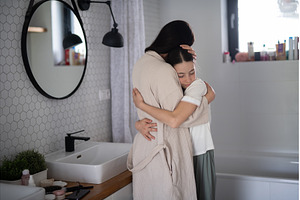 Mom hugging daughter during, a Person Photo by HalfPoint