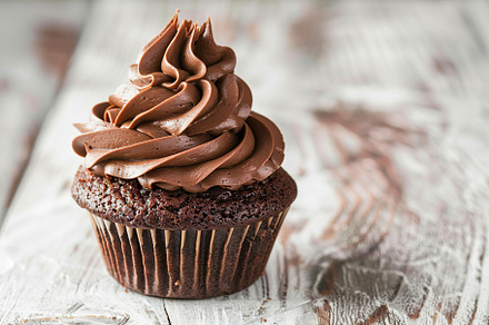 Chocolate cupcake with whipped cream on wooden table, a Food & Drink Photo by AlyaAnd