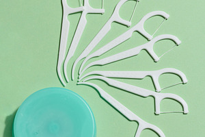 A flat lay composition of white dental floss picks fanned out ar, a Health & Medical Photo by ndanko