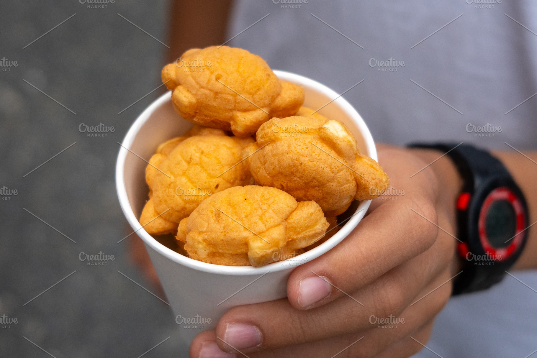 Hands holding cup of turtle shaped taiyaki in Osaka, Japan, a Food & Drink Photo by GoodGoods