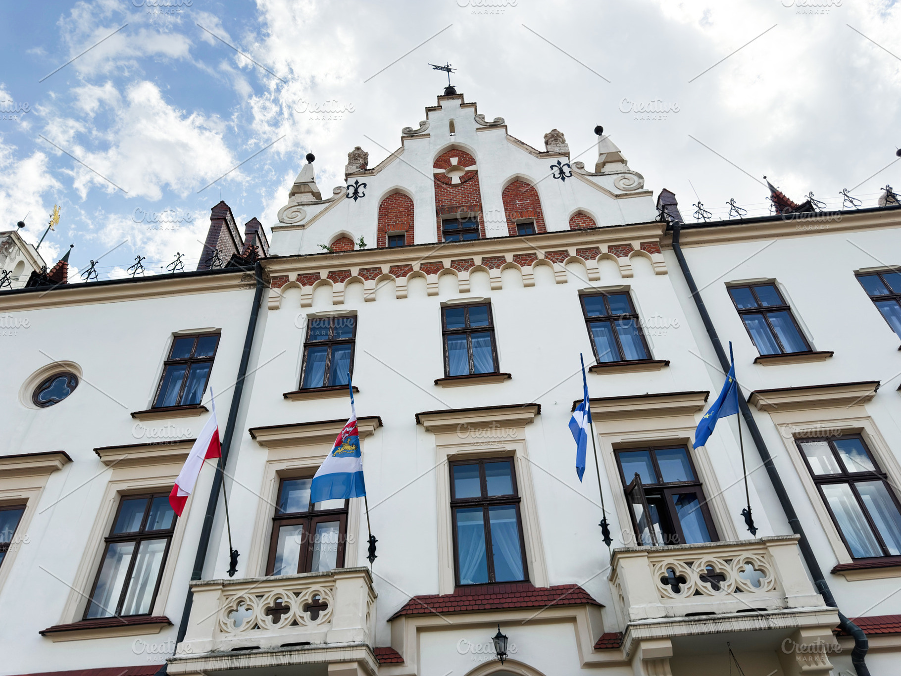 Historic town hall facade with flags and ornate balconies in Rze, a Photo by AS photostudio