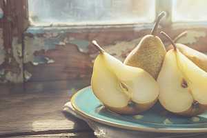 Yellow ripe pears in plate on wooden table, a Food & Drink Photo by AlyaAnd