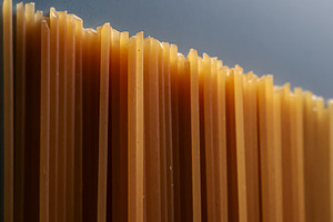 Dry whole wheat spaghetti pasta standing upright, creating an abstract textured, a Photo by Studio ANNA