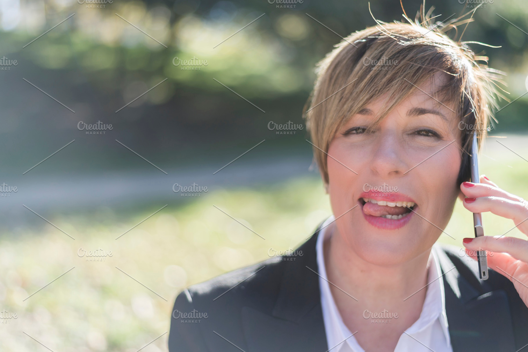 Smiling businesswoman talking on phone outdoors, a Photo by RF Images