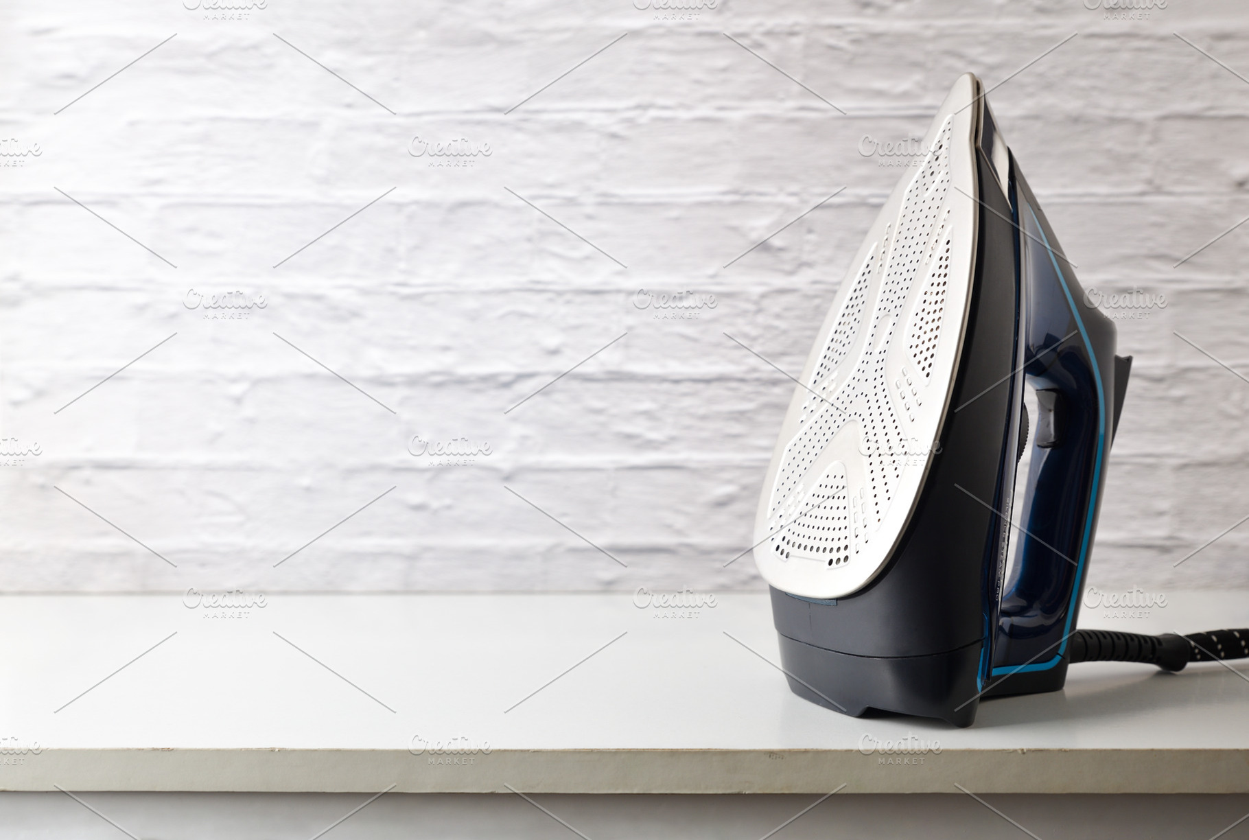 Steam iron on white wooden furniture and white brick background, a Technology Photo by Davizro's Market