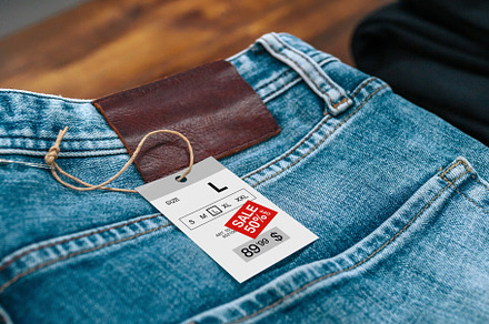 Detail of label with discount price over a blue jeans pants on vintage store, a Business Photo by davidpereiras