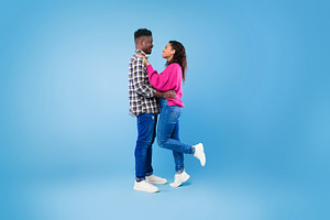 Side view of happy young African American couple in casual wear hugging and loo, a Photo by Prostock-Studio