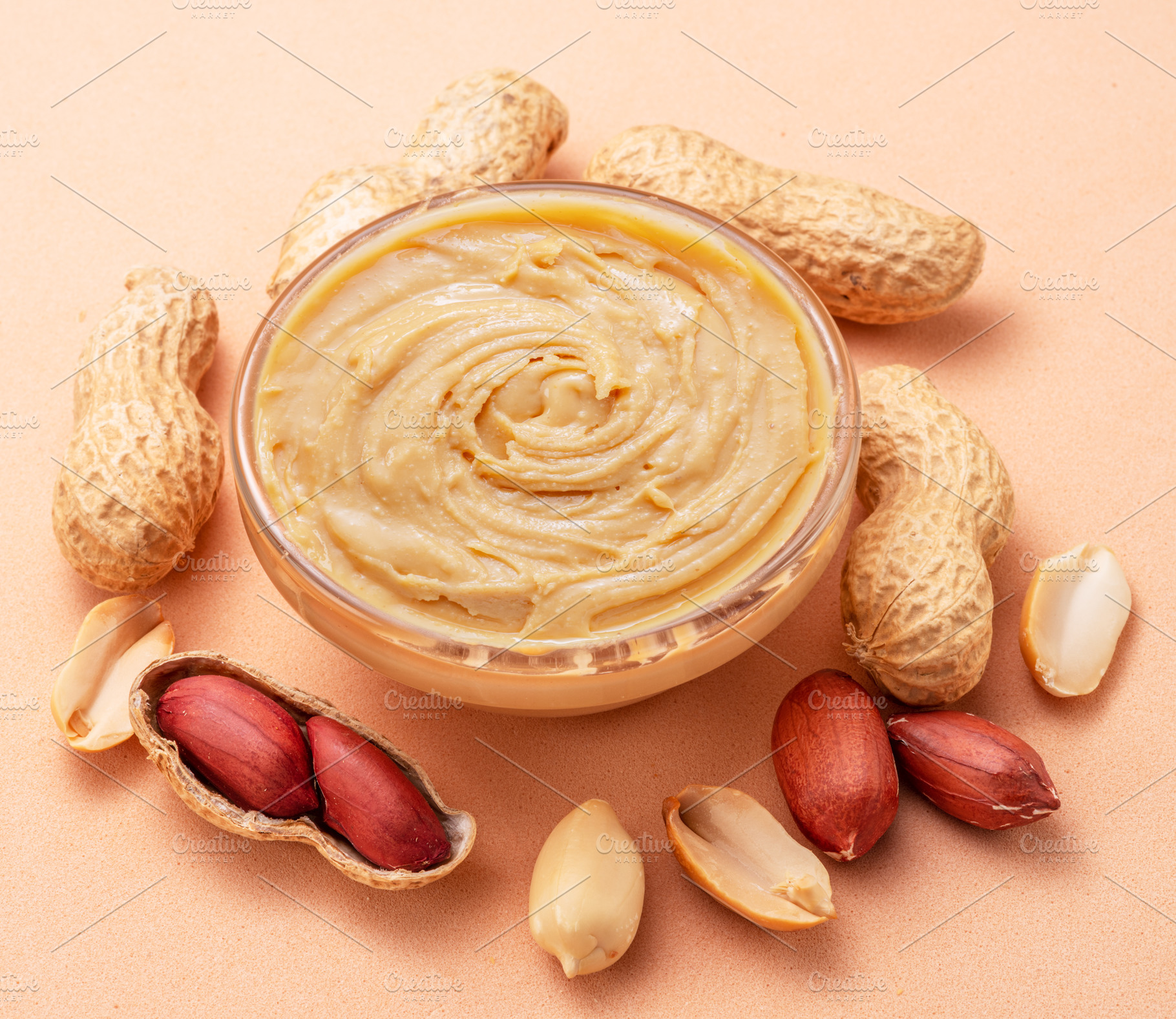 Bowl of peanut butter and peanuts around it on beige background., a Food & Drink Photo by Volff