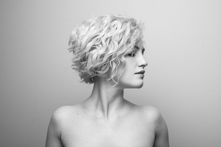 Headshot of gorgeous attractive young lady with curly hair smiling. Black and w