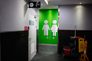 Clean public restroom area with gender signs and janitorial cleaning supplies, a Photo by AS photostudio