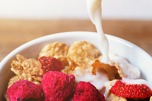 Pouring milk into bowl of cereal with raspberries and strawberries for breakfas, a Food & Drink Photo by Antonio Gravante Market