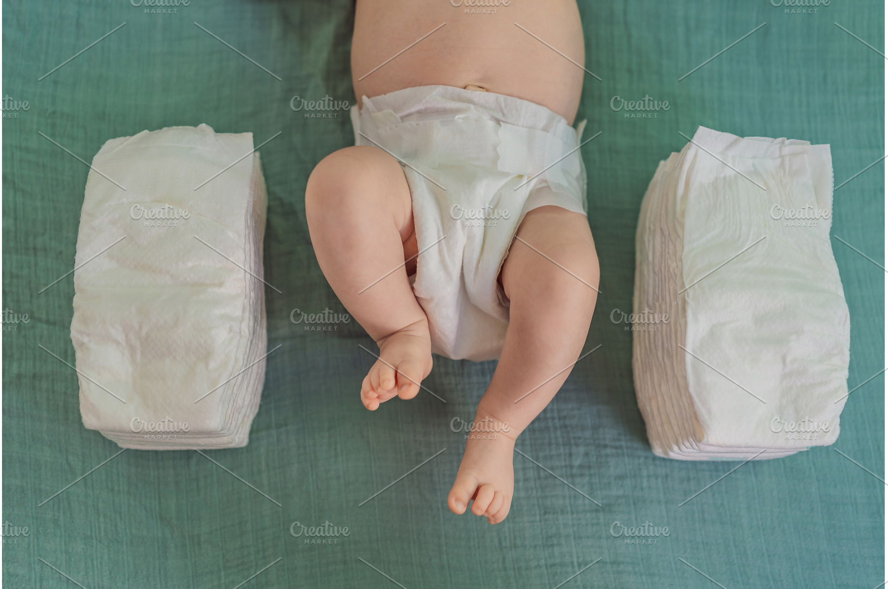 Baby lying between two stacks of, a Person Photo by Elizaveta Galitskaya