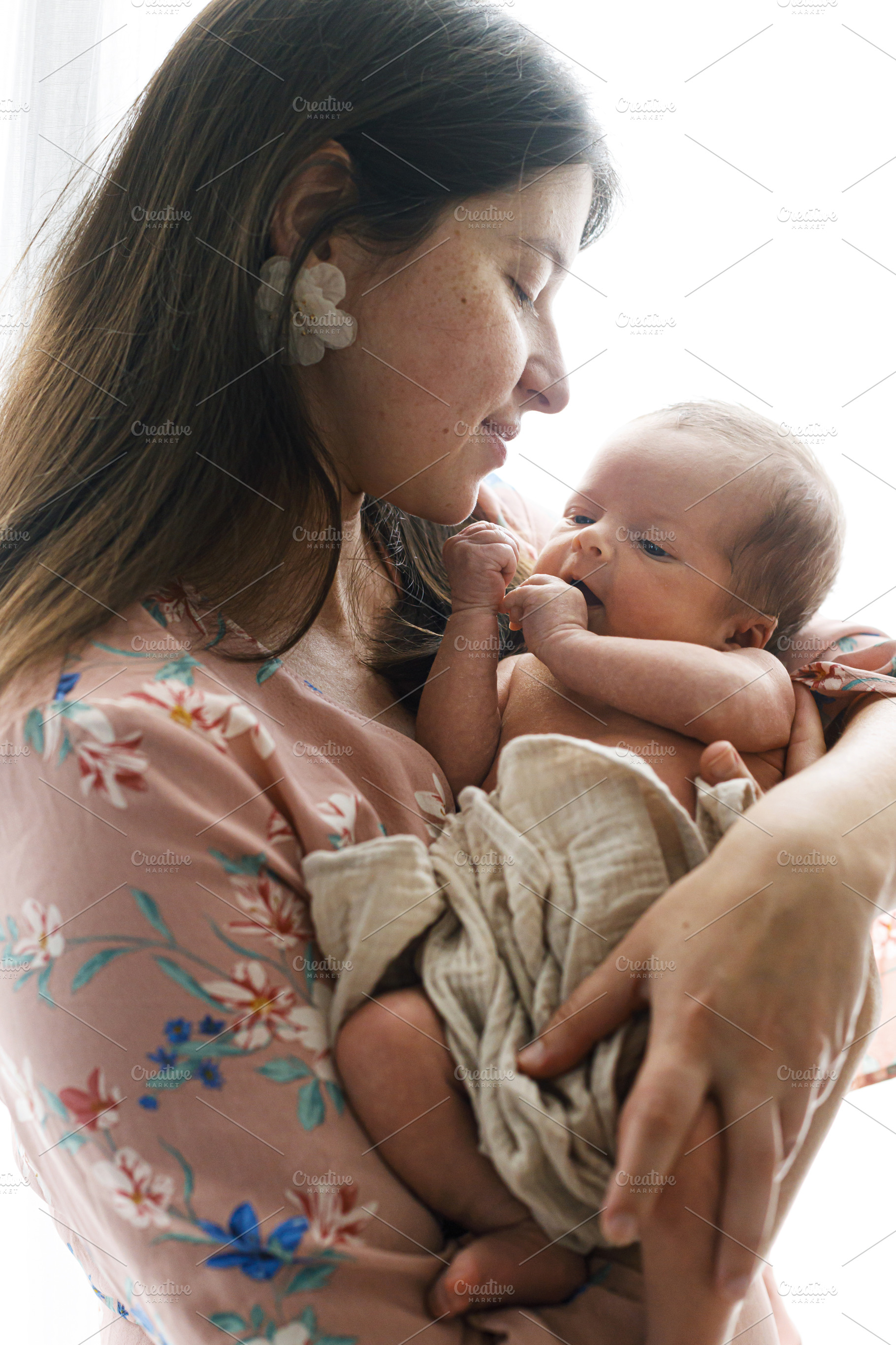Happy Mother holding cute little baby in window light, close up., a Person Photo by Sonjachni
