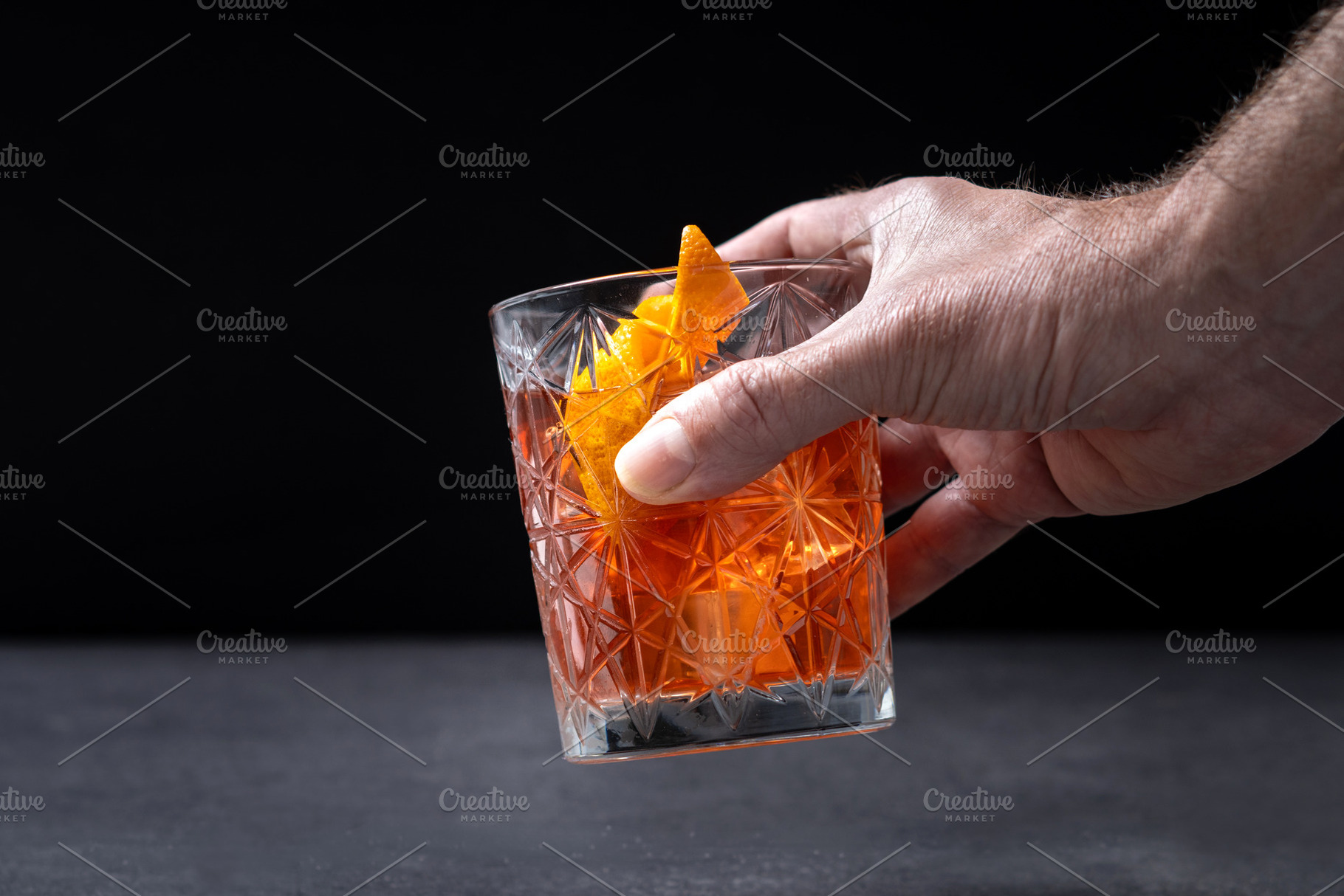 Hand Holding Old Fashioned Cocktail with Orange Peel in Crystal Glass, a Food & Drink Photo by etorres69