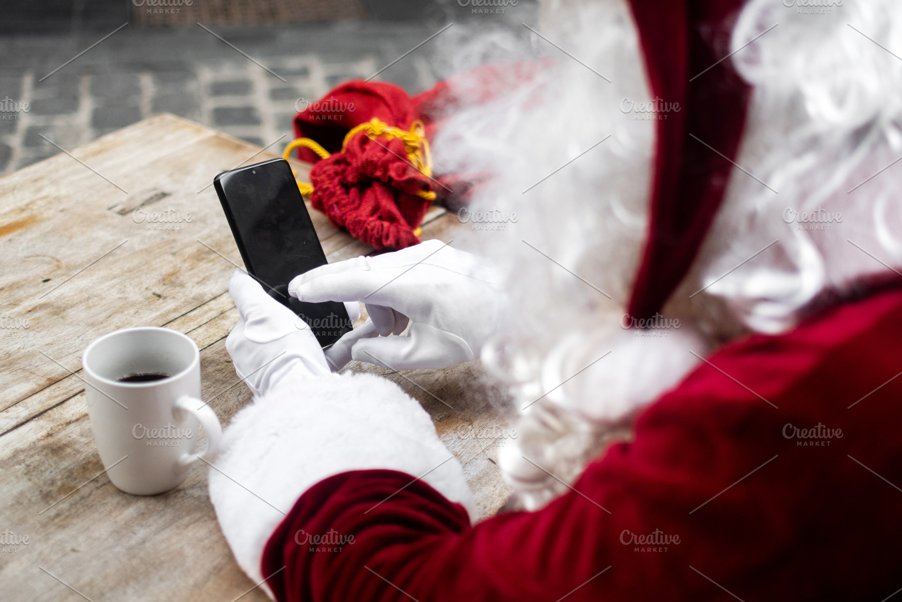 Santa Claus using smartphone while having coffee at outdoor cafe, a Person Photo by etorres69