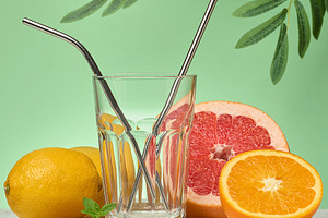 Grapefruit, orange and empty glass on green background, a Photo by ndanko