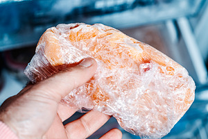a man grips frozen chicken from the freezer, a Photo by Nito