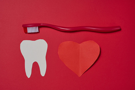 Red toothbrush, white paper tooth cut out and red paper heart pl