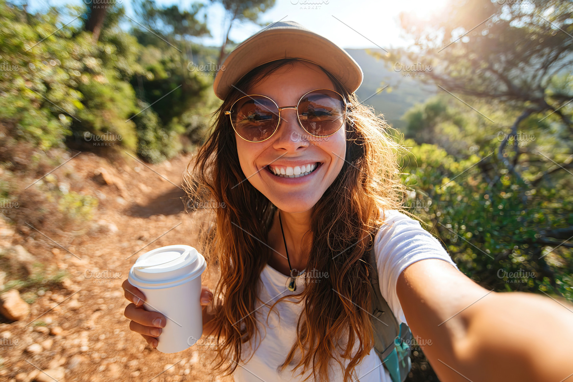 Enjoying nature while taking selfies on a sunny hiking trail with coffee in han, a Person Photo by AlyaAnd