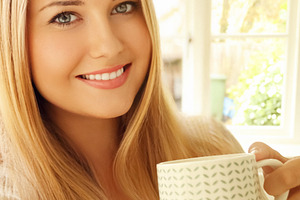 Blonde woman having a coffee, milk or tea in a mug, smiling, sta, a Person Photo by Studio ANNA