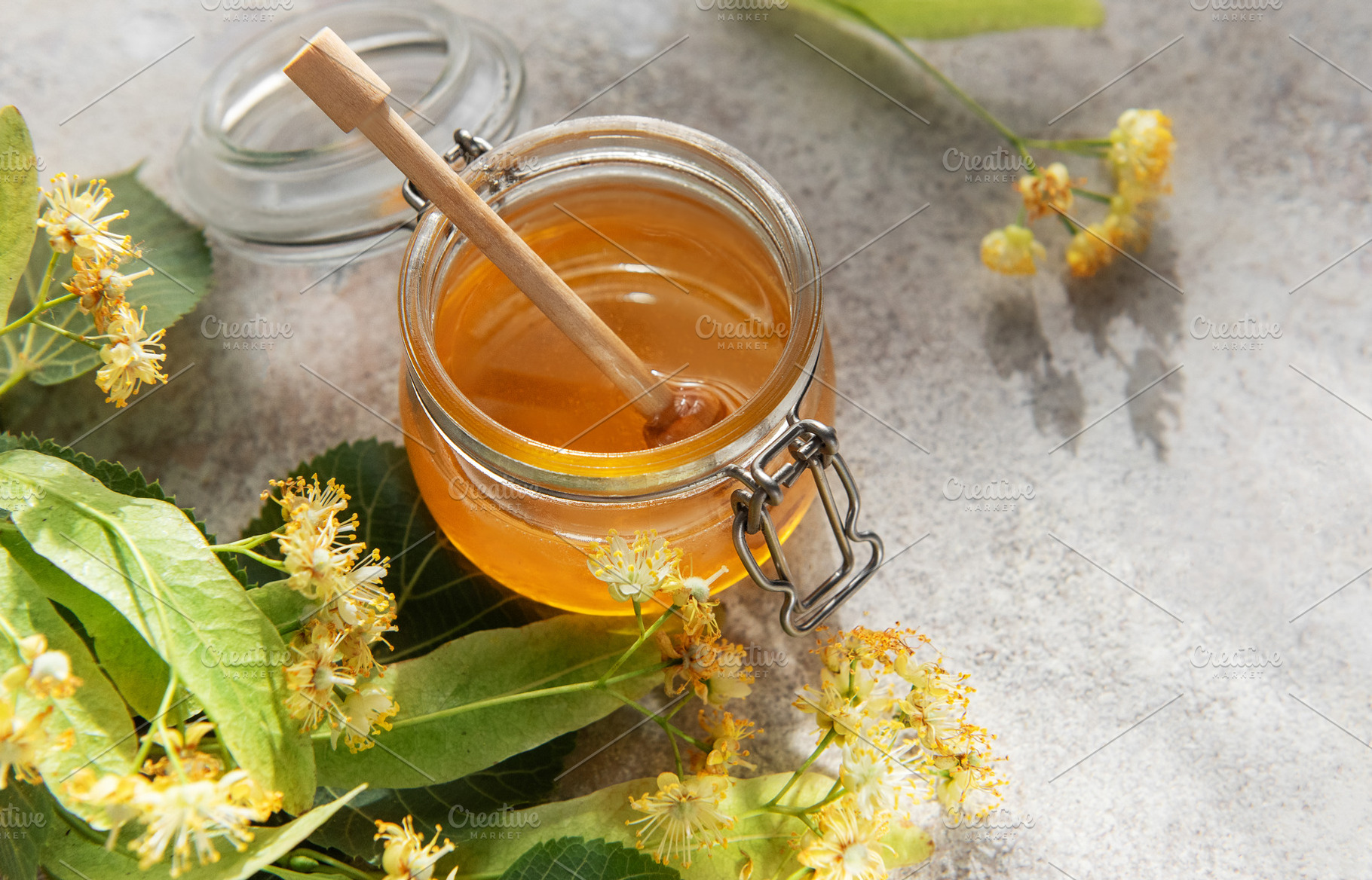 Linden honey jar with wooden dipper and fresh flowers, a Food & Drink Photo by Olena Rudo