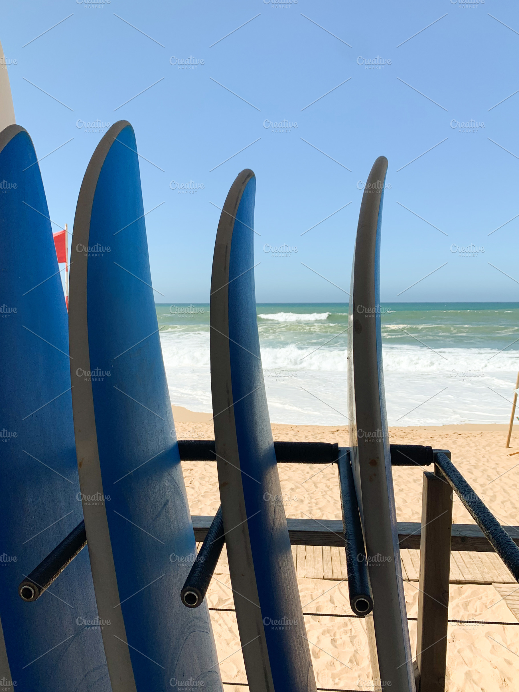 Surfboards lined up on a sandy beach with ocean waves in the bac, a Holiday Photo by sebastianaraw