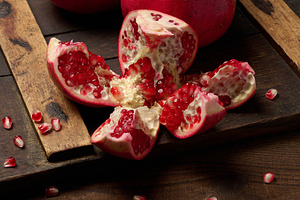 A fresh pomegranate slice with brightly colored seeds on a brown, a Food & Drink Photo by ndanko