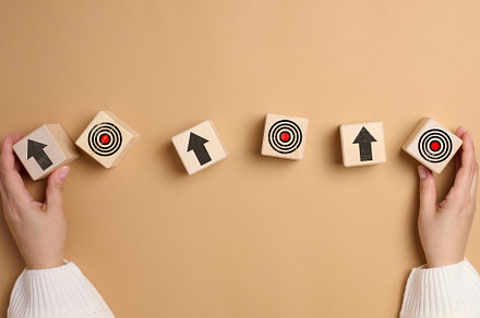 A woman's hand holds wooden cubes with arrows and a drawn target, a Business Photo by ndanko
