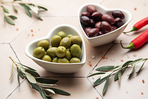 Heart shaped bowls containing green and black olives, olive bran, a Food & Drink Photo by Olena Rudo
