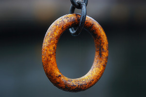 Rusty metal ring hanging from a chai, a Photo by Tanuart
