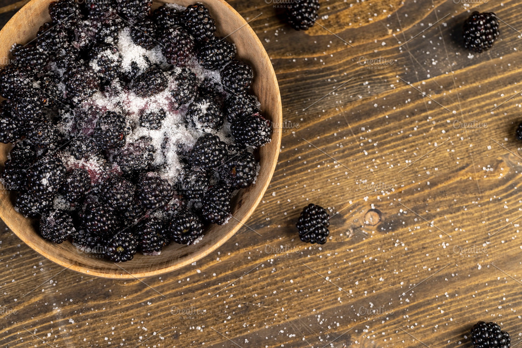 blackberries in a wooden bowl sprinkled with sugar , sour but ripe blackberries, a Photo by rsoollAI