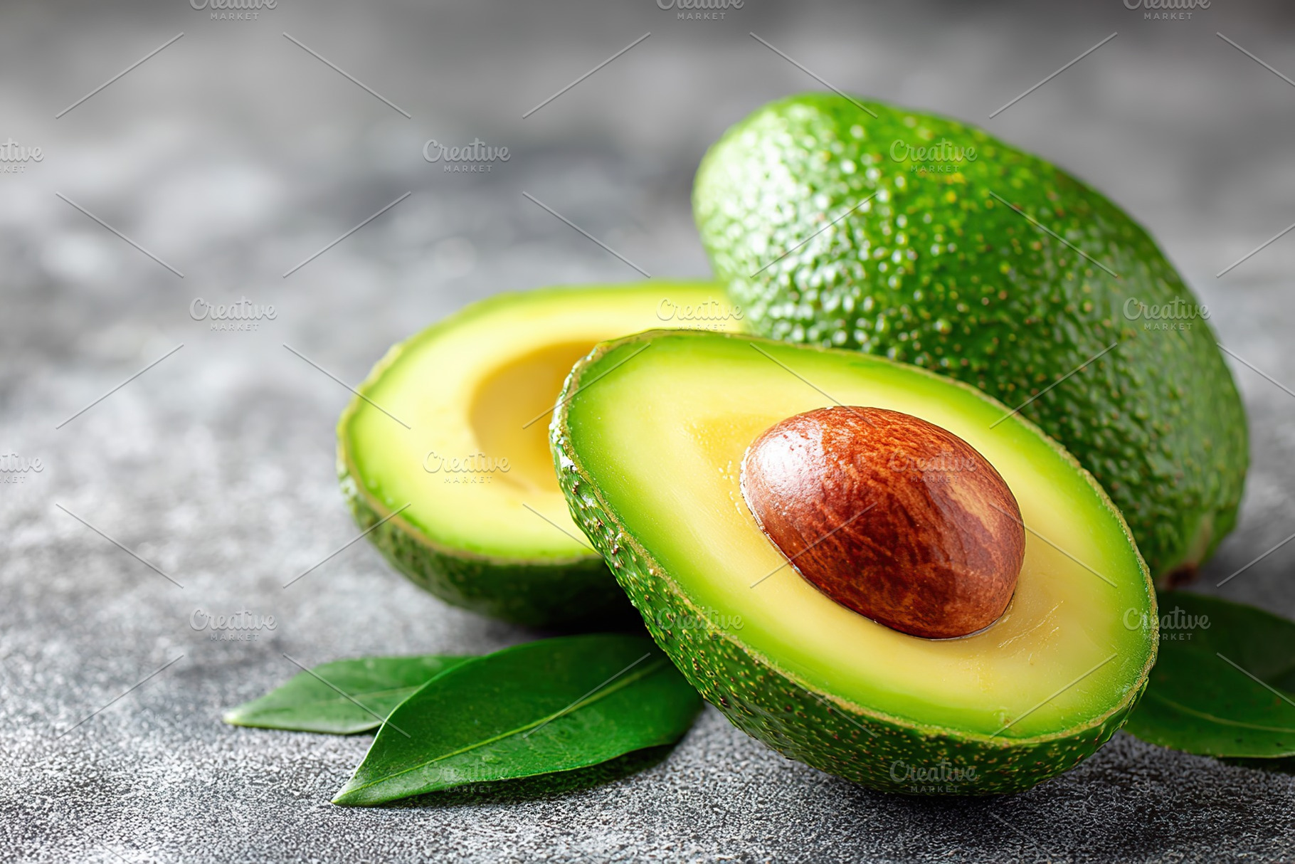 Bright green avocado halves with shiny texture and smooth flesh on a gray backg, a Food & Drink Photo by AlyaAnd