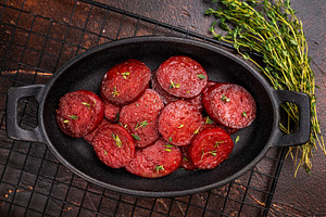 Fried Turkish sucuk (sujuk) slices in a cast iron pan with thyme, a Photo by composter-box@mail.ru