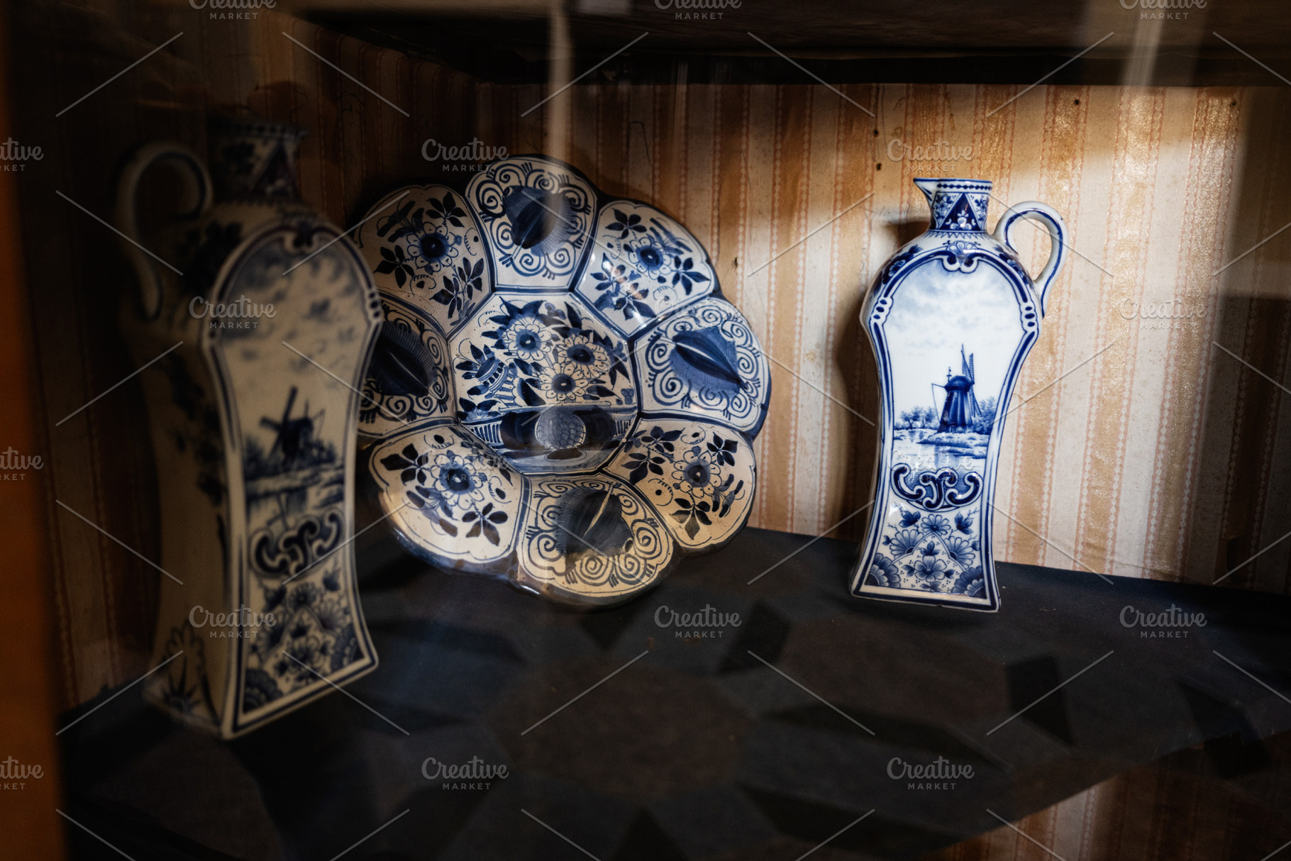 Antique blue white porcelain pieces with intricate floral and windmill designs, a Photo by AS photostudio