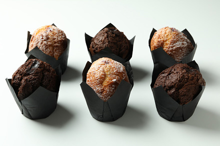 Chocolate muffins on white background, close up, a Food & Drink Photo by AtlasStudio