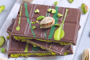 Dubai style milk chocolate bar with pistachio and kadaifi filing, lying on cutt, a Food & Drink Photo by iuliia_n