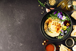 Gourmet Hummus with Edible Flowers and Spices on Dark Background, a Food & Drink Photo by Natalia Klenova's Shop