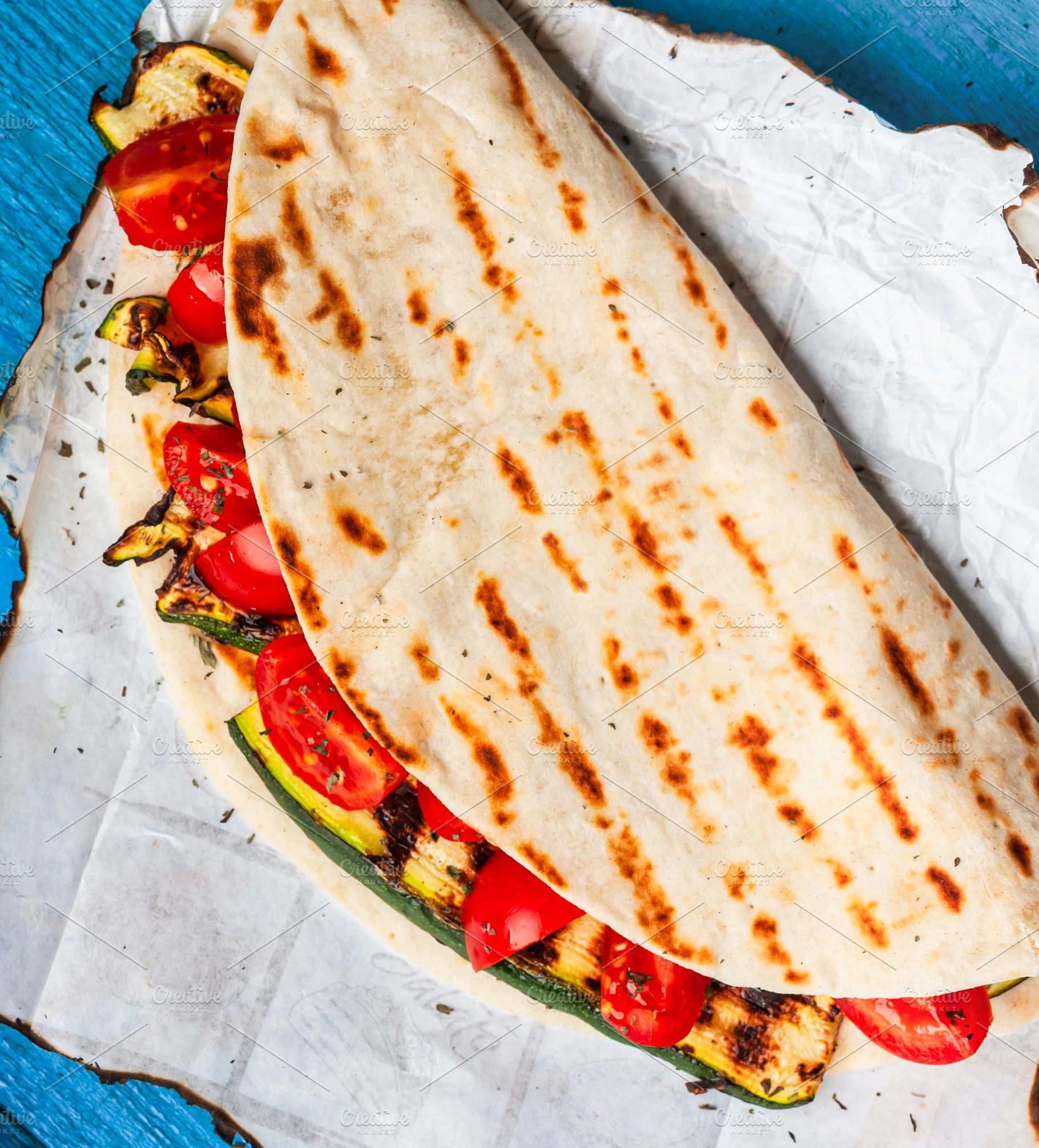 Piadina with grilled zucchini and tomatoes on burnt baking paper, a Food & Drink Photo by Antonio Gravante Market
