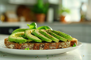 Toasted rye bread with sliced avocado and herbs in plate on table on blurred ki, a Food & Drink Photo by AlyaAnd