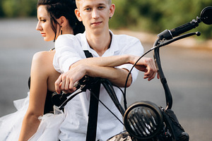 A couple of newlywed freaks on a black custom bike, a Person Photo by Weddings, People, Travel
