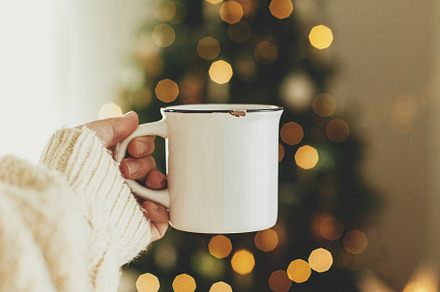 Hand holding stylish white cup against stylish festive christmas, a Holiday Photo by Sonjachni